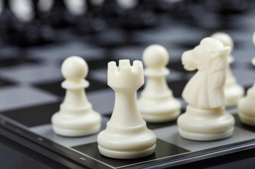 Close-up of white chess pieces on a board, focusing on a rook and knight