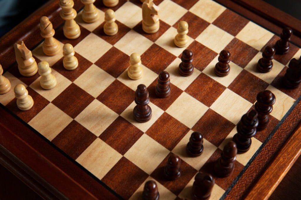 wooden chessboard with beige and brown squares showcasing an ongoing game