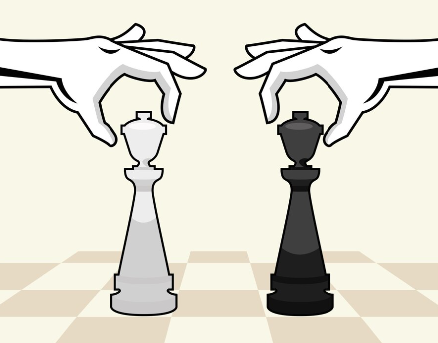Two hands poised to move white and black kings on a chessboard