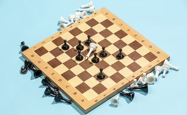 Chessboard next to which chess pieces are scattered
