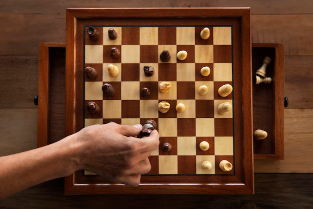 A man makes a move on a chessboard, top view