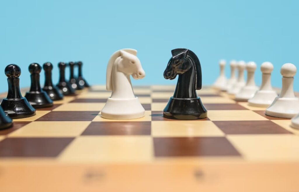 White and black knights face off on a chessboard with a blue backdrop