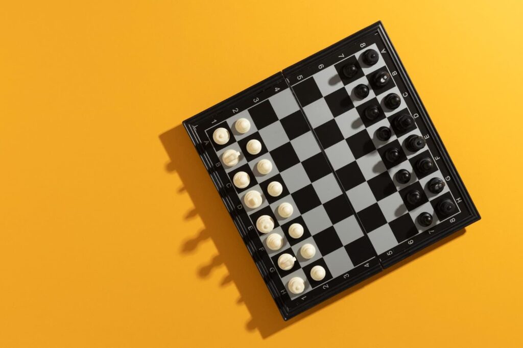 Top view of chess board with pieces on yellow background