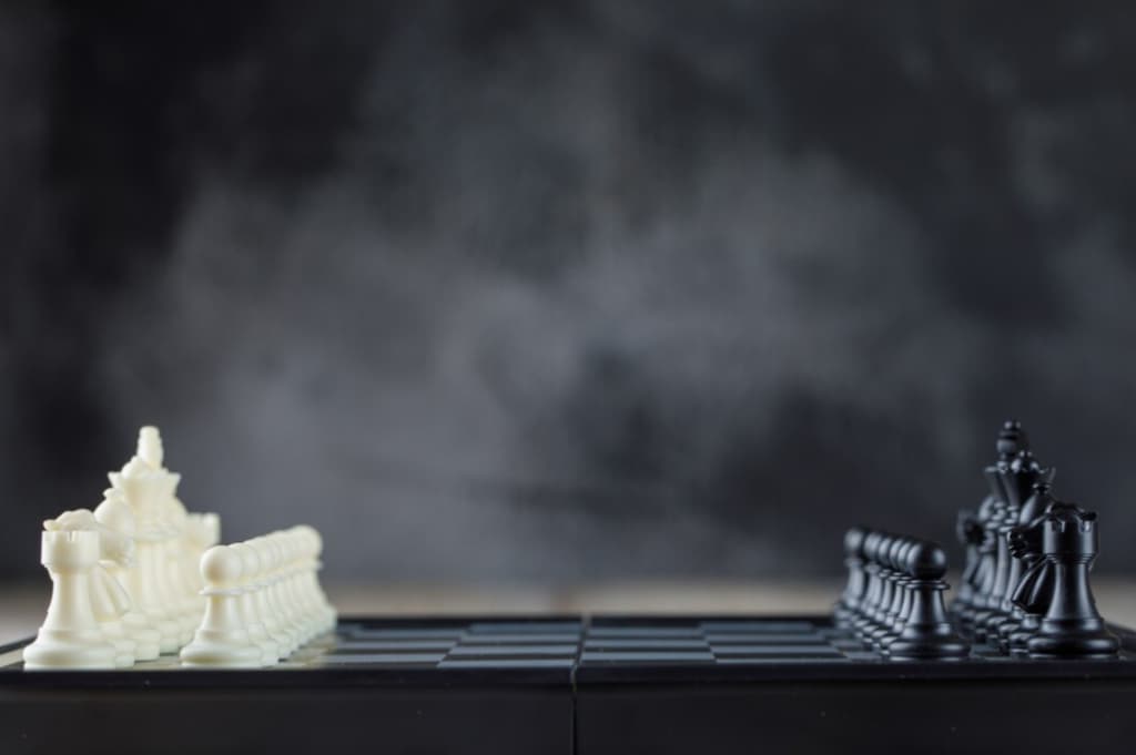 White and black chess are positioned facing each other on a chessboard against a dark background
