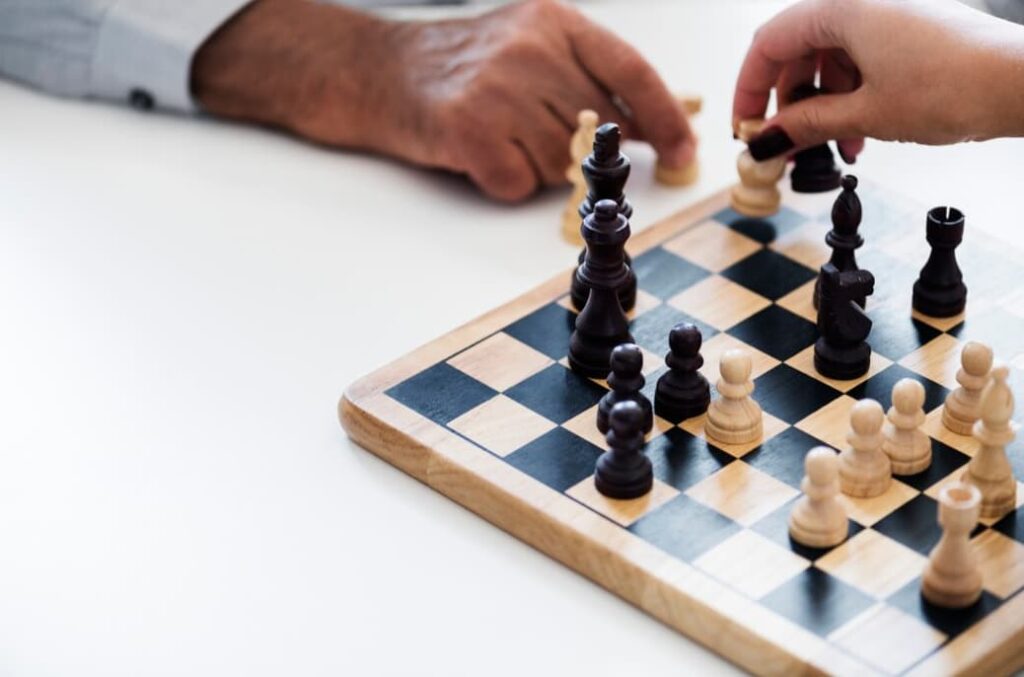 Two hands, one moves a black chess piece and the other a white one